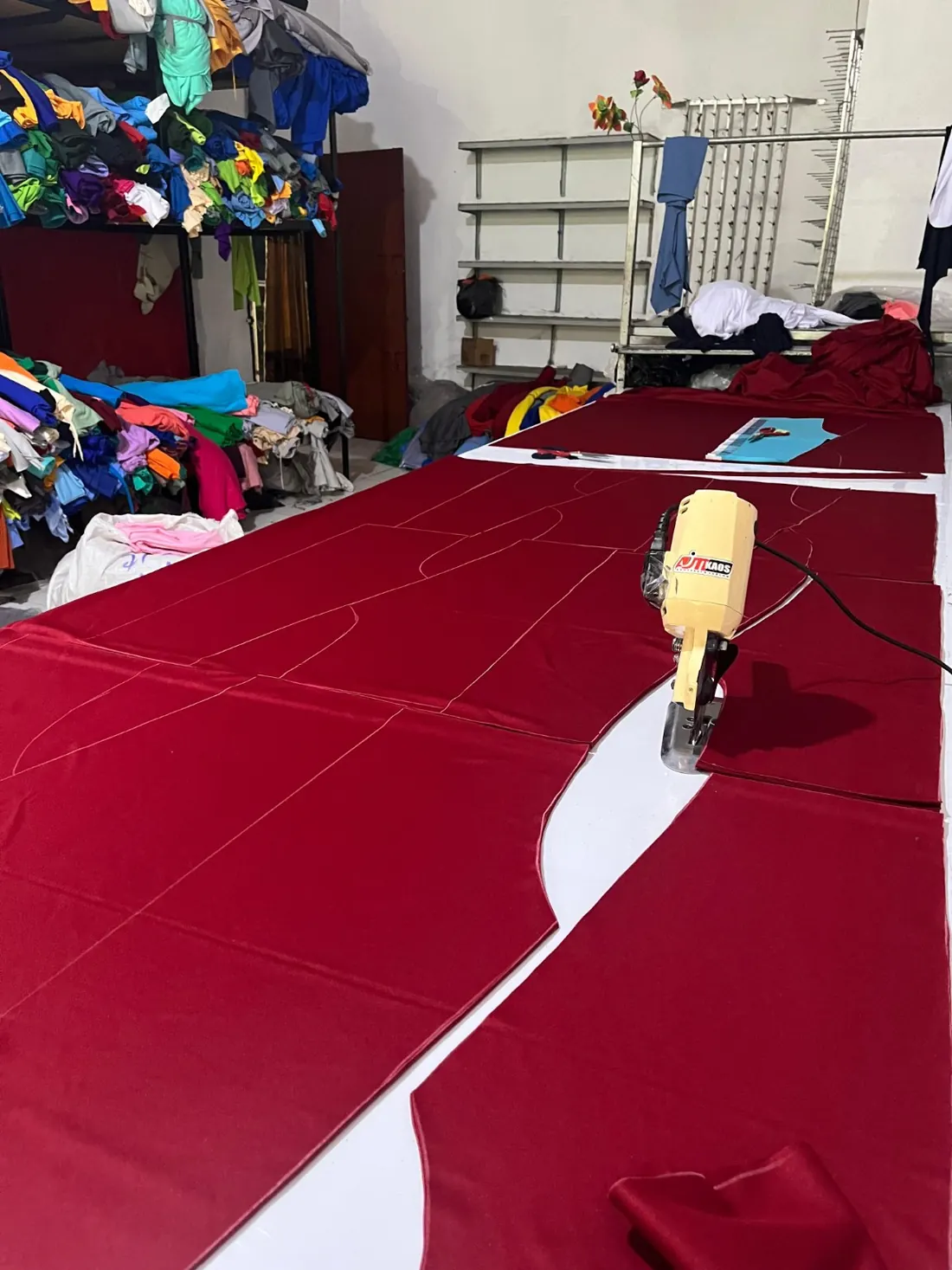 Proses pemotongan kain merah di meja potong AJM